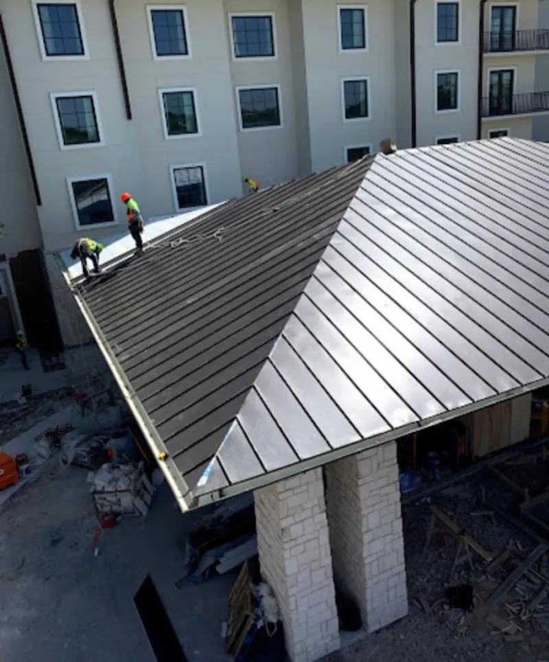Crew installing standing seam metal roof panels on a commercial project in Dickinson